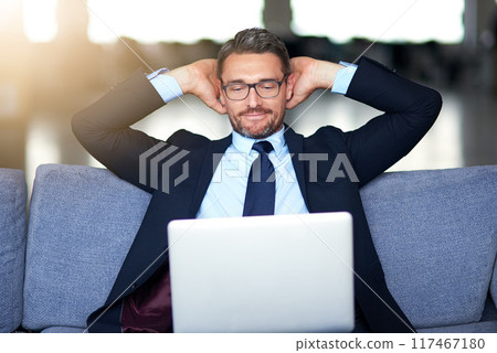 Business, man and relax on sofa with laptop in office, working break and employee done for online project. Happy, company and corporate job in workplace, email and report submission for target 117467180