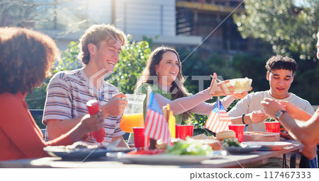 Friends, group and eating bbq in garden on terrace with conversation, holiday or social event in summer. People, barbecue and reunion on patio with food, talking or celebration with bonding or drinks Friends, group and eating bbq in garden on terrace with conversation, holiday or social event in summer. People, barbecue and reunion on patio with food, talking or celebration with bonding or drinks 117467333