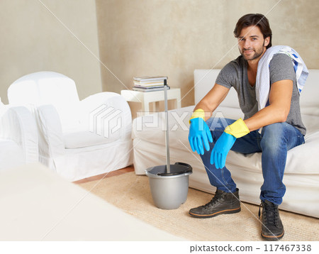 Man, resting and sofa after cleaning house with mop, gloves or bucket during morning in Colombia. Professional cleaner, male domestic or char with tired smile in modern home for mockup or portrait Man, resting and sofa after cleaning house with mop, gloves or bucket during morning in Colombia. Professional cleaner, male domestic or char with tired smile in modern home for mockup or portrait 117467338