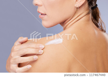 Woman, shoulder and cream in studio for skincare, ointment and spf or cosmetics on blue background. Person, lotion and pamper for dermatology, grooming and moisturizer for hydration or skin treatment 117467440