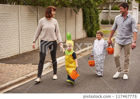 Family, happy and parents for children in halloween, together and trick or treating for candy. Costume, mother and father smile walking with kids for bonding, support and love for celebration in road 117467778