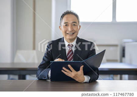 拿著文件並且看照相機的資深商人 117467780