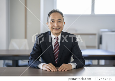 Senior businessman with earphones smiling and looking at camera 117467840