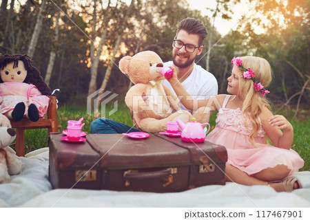 Father, tea party and girl kid in garden for nature picnic with toys, teddy bear drink and suitcase for table. Daughter, dad and memory together for playing or fun, bonding and love in outdoor. 117467901