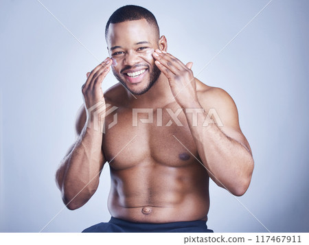 Black man, apply lotion and studio portrait for skincare, ointment and cosmetics on blue background. Person, cream and facial for dermatology, grooming and moisturizer for hydration or skin treatment Black man, apply lotion and studio portrait for skincare, ointment and cosmetics on blue background. Person, cream and facial for dermatology, grooming and moisturizer for hydration or skin treatment 117467911