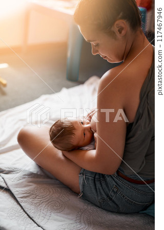 Breastfeeding, mother and baby on bed in bedroom for nutrition, growth development or digestive health. Lens flare, back and woman with newborn child for natural milk, wellness or bonding in home Breastfeeding, mother and baby on bed in bedroom for nutrition, growth development or digestive health. Lens flare, back and woman with newborn child for natural milk, wellness or bonding in home 117467946