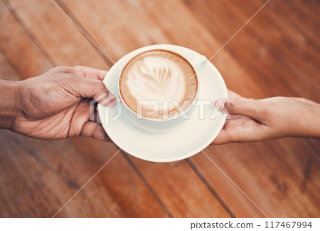 Service, customer and serving coffee to a cafe client and giving a cup of hot and fresh drink with milk foam at coffeeshop. Closeup of hands holding cappuccino with beautiful cream of latte art 117467994