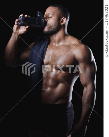 Black man, drink and water or protein shake in studio for hydration, exercise and fitness or workout. Bodybuilder, wellness and liquid by dark background for African athlete, towel and heath 117468021