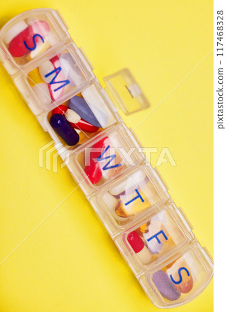 Health, daily medication and pill box in studio for prescription, healthcare or anxiety disorder on yellow background. Above, wellness and container with drugs for depression, supplements or mockup 117468328
