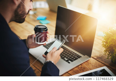 Coffee, phone and laptop with man at coworking desk with blank screen for social media break on tech. Morning, web designer and creative job with latte and mobile scroll at office with design work 117468329