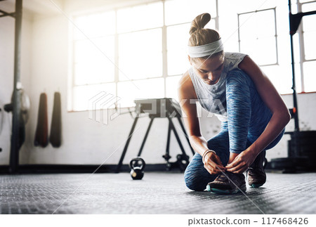 Woman, tie and shoes on floor for exercise, workout and fitness goals in gym with commitment. Athlete, ready and shoelace on ground of sports club for training, health and wellness with motivation Woman, tie and shoes on floor for exercise, workout and fitness goals in gym with commitment. Athlete, ready and shoelace on ground of sports club for training, health and wellness with motivation 117468426