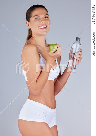 Portrait, woman and apple with water for healthy diet, fitness and nutrition in grey studio background. Wellness, female person and fruit happy with drink for organic meal, snack or vegan eating Portrait, woman and apple with water for healthy diet, fitness and nutrition in grey studio background. Wellness, female person and fruit happy with drink for organic meal, snack or vegan eating 117468432