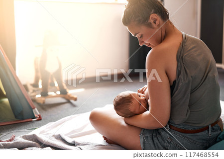 Breastfeeding, mother and baby on bed for nutrition, growth development or digestive health in bedroom. Lens flare, back and woman with newborn child for natural milk, wellness or bonding in home 117468554