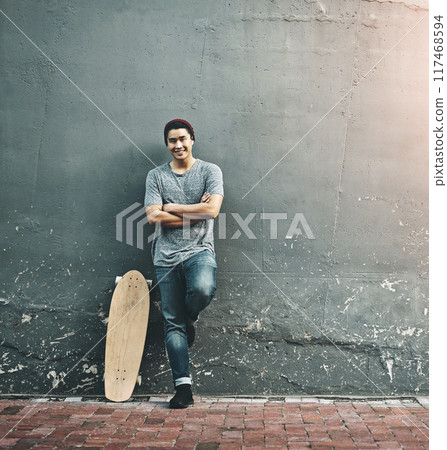 Fashion, skateboard and portrait of man in city with trendy style, cool outfit and crossed arms outdoors. Happy, confidence and person on wall background for skateboarding, weekend fun and holiday 117468594