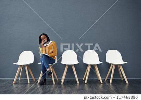 Wait, bored and black woman for recruitment, hiring or meeting for interview in office. Chairs, tired and female person as candidate of human resources, exhausted or impatient with paper in workplace 117468880