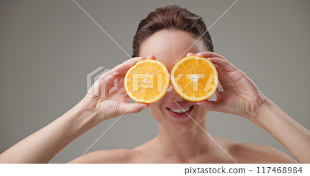 Beauty, health, cosmetics, anti-aging therapy and skin care concept - young beautiful brunette Caucasian woman holding half a orange, concept of freshness, vitamins and nutrients Beauty, health, cosmetics, anti-aging therapy and skin care concept - young beautiful brunette Caucasian woman holding half a orange, concept of freshness, vitamins and nutrients 117468984