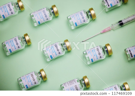 Healthcare, injection and glass bottle of vaccine by green background, treatment or illness prevention. Medical, insulin and syringe for disease, coronavirus or diabetes for immune wellness in studio 117469109