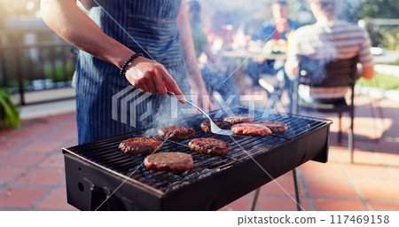 Barbecue, lunch and man with burgers outdoor backyard for meal at reunion, social event or party on terrace. Grill, food and male person cooking patty, beef or meat for bbq dish on weekend at home. 117469158