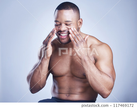 Black man, apply cream and glow in studio for skincare, ointment and cosmetics on blue background. Person, lotion and pamper for dermatology, grooming and moisturizer for hydration or skin treatment Black man, apply cream and glow in studio for skincare, ointment and cosmetics on blue background. Person, lotion and pamper for dermatology, grooming and moisturizer for hydration or skin treatment 117469172