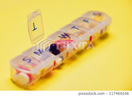 Daily medicine, healthcare and pill container in studio for prescription, health or anxiety disorder on yellow background. Empty, wellness and box with drugs for depression, supplements or vitamins 117469206