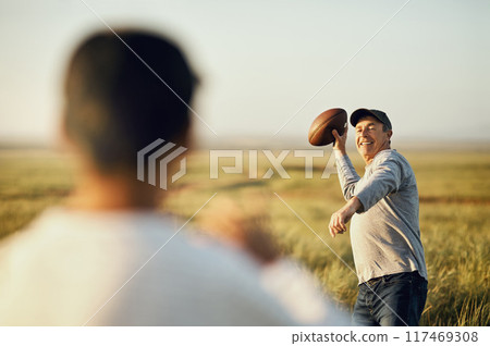 Son, dad and football with teaching in nature for outdoor sports, child development and exercise together. Happy, man and throw with kid on grass field for bonding, practice and fathers day in Texas 117469308