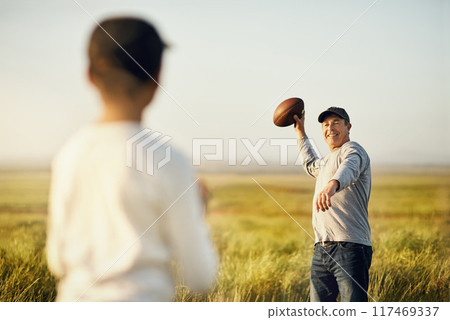 Kid, dad and football with throw in nature for outdoor sports, teaching and child development. Countryside, man and son on grass field with practice, exercise and bonding on fathers day in Dallas Kid, dad and football with throw in nature for outdoor sports, teaching and child development. Countryside, man and son on grass field with practice, exercise and bonding on fathers day in Dallas 117469337