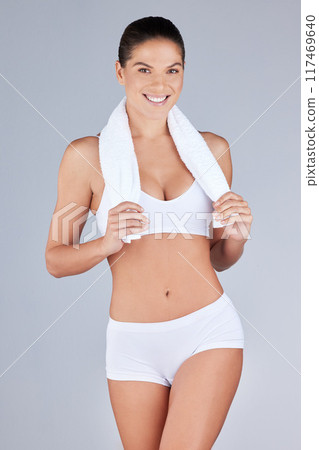 Portrait, woman or athlete body smiling for health, fitness or workout in grey studio background. Wellness, female person and towel happy for training, weight loss or exercise in active underwear 117469640