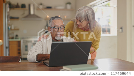 Senior couple, kitchen and laptop with internet connection for reading news and pension article. Interracial marriage, old man and woman with computer in home for online faq about retirement research 117469644
