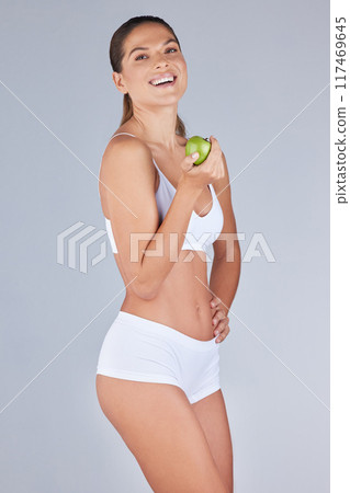Studio portrait, woman and apple for nutrition, confidence and health for transformation. Underwear, wellness and food or fruit for weight loss, diet and results with athlete by white background 117469645