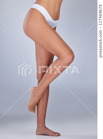 Woman, legs and smooth skin in studio for epilation, skincare and hair removal on blue background. Female person, soft and waxing or shaving for clean glow, grooming and cosmetics or dermatology 117469678