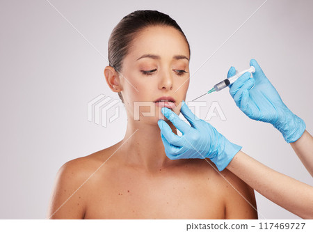 Woman, beauty and needle in hand for plastic surgery with facelift and medical procedure in studio. Female client, cosmetic transformation and surgeon syringe for liquid collagen by white background Woman, beauty and needle in hand for plastic surgery with facelift and medical procedure in studio. Female client, cosmetic transformation and surgeon syringe for liquid collagen by white background 117469727