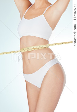 Woman, underwear and tape measure for weight loss, fitness and healthy diet in white studio background. Female person, progress or stomach check for wellness, exercise and liposuction or tummy tuck 117469752