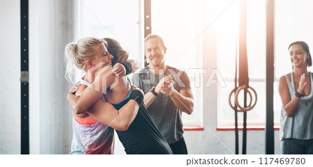 Fitness, women and celebration hug at gym for support after workout, sports exercise or training challenge. Happy girls, embrace and friends, people smile and achievement together for wellness club 117469780