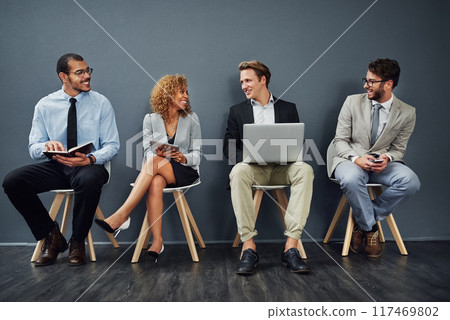 Corporate people, technology and waiting room in conversation or networking for job search opportunity. Group of business candidate talk in queue, chair and recruitment lobby by gray wall background Corporate people, technology and waiting room in conversation or networking for job search opportunity. Group of business candidate talk in queue, chair and recruitment lobby by gray wall background 117469802