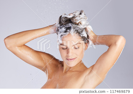 Naked woman, shower and shampoo for hair care in studio with water droplets and soap for cleaning. Nude, female person and foam for hygiene, scalp and skincare for wellness by grey background 117469879