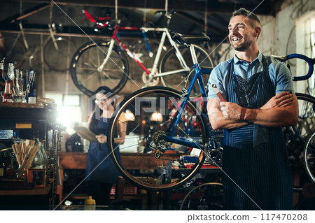 Man, thinking and arms crossed at work in bicycle repair shop or maintenance garage. Bike, mechanic and service with a professional handyman for startup, small business and workshop for fixing 117470208