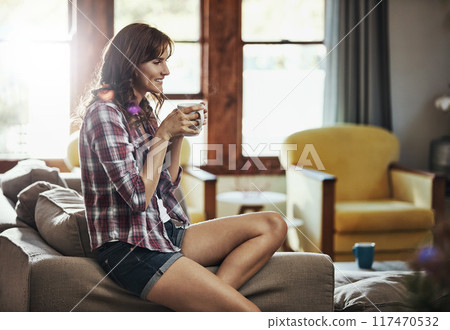 Coffee, happy and thinking with woman on sofa in living room of home for morning or weekend time off. Drink, relax or smile and person in apartment with fresh caffeine beverage for break or wellness 117470532