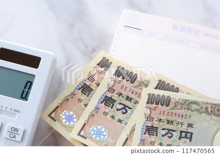 An open bank passbook, 10,000 yen notes, and a calculator on a table 117470565