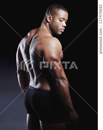 Back, bodybuilder and black man in underwear for fitness, health and body care in studio. African athlete, confidence and muscles or biceps by dark background for wellness, training and results 117470682