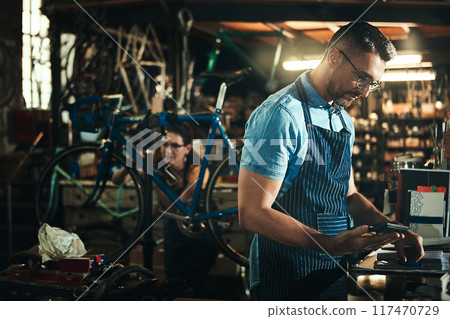 Man, bicycle mechanic and expenses with calculator in small business for fix, repair or maintenance. Male person, cycle engineer or bike technician checking bill for job or equipment at workshop Man, bicycle mechanic and expenses with calculator in small business for fix, repair or maintenance. Male person, cycle engineer or bike technician checking bill for job or equipment at workshop 117470729