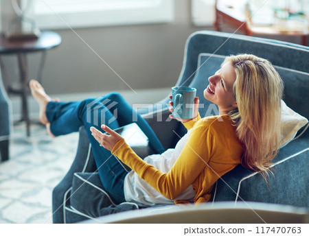 House, tablet and woman on couch, coffee and rest in living room, morning and happy with social media. Relax, calm and girl with break, smile or peace in lounge, cozy and person with tea in apartment 117470763