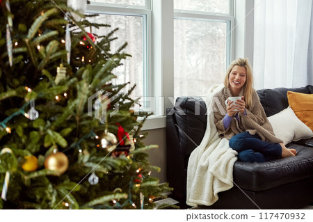 Christmas, happy woman and tea on house sofa with smile while thinking of memory. Portrait of lady with hot chocolate or coffee cup to relax for festive holiday, season or winter vacation celebration 117470932