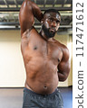 Shirtless black man working on his flexibility at the gym 117471612