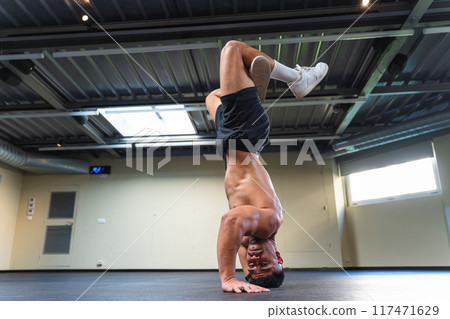 Young man with an athletic body practicing breakdance indoors 117471629
