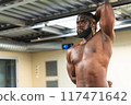Black bodybuilder stretching his muscles before strength training 117471642