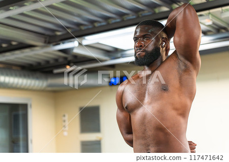 Black bodybuilder stretching his muscles before strength training Black bodybuilder stretching his muscles before strength training 117471642