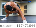 Young male athlete stretching his legs prior to training 117471644