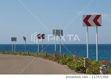 Curve and chevron markers on a road with a view of the ocean Curve and chevron markers on a road with a view of the ocean 117471906