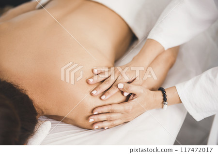 Process of shoulder massage in professional salon, close-up. Therapist working with female body, faceless people, movement, selective focus. 117472017