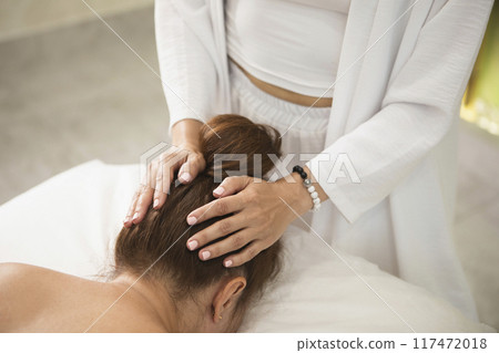 Process of head massage in professional salon, close-up. Therapist working with woman laying face down, faceless people, selective focus. 117472018